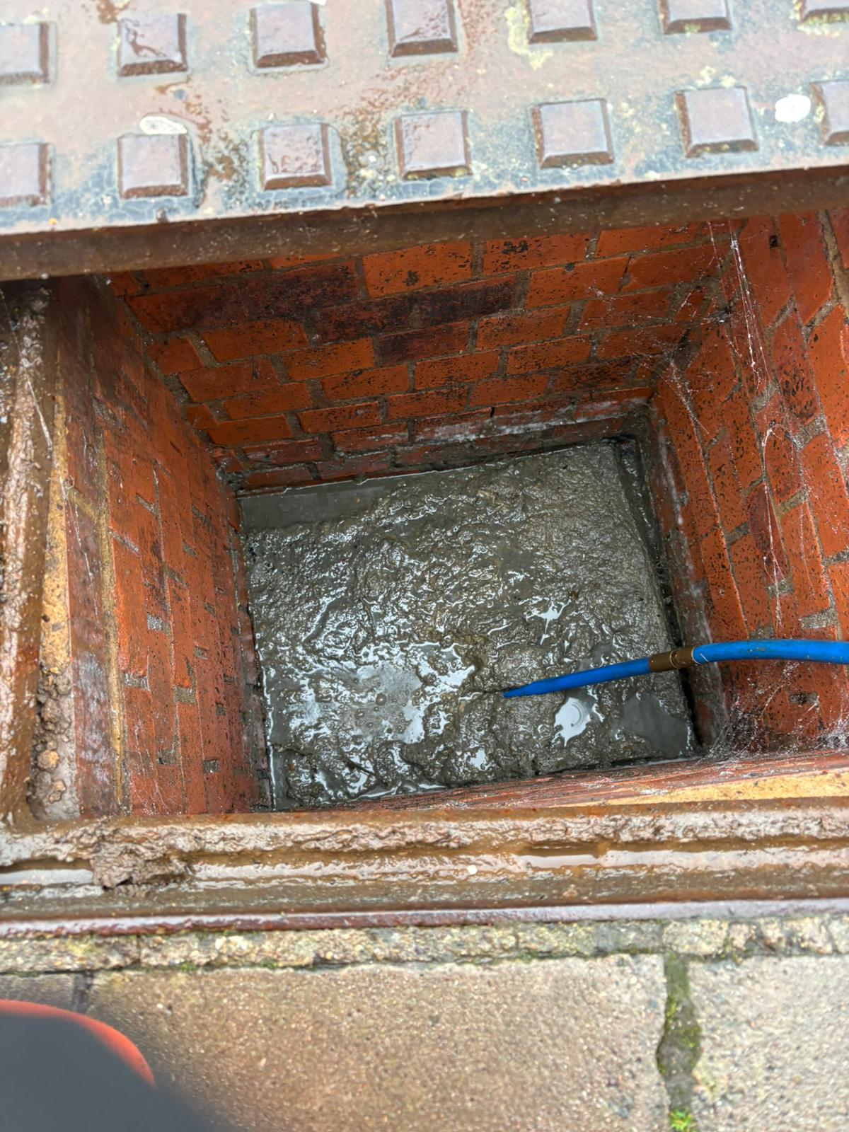 Brick manhole heavily silted before cleaning and repair