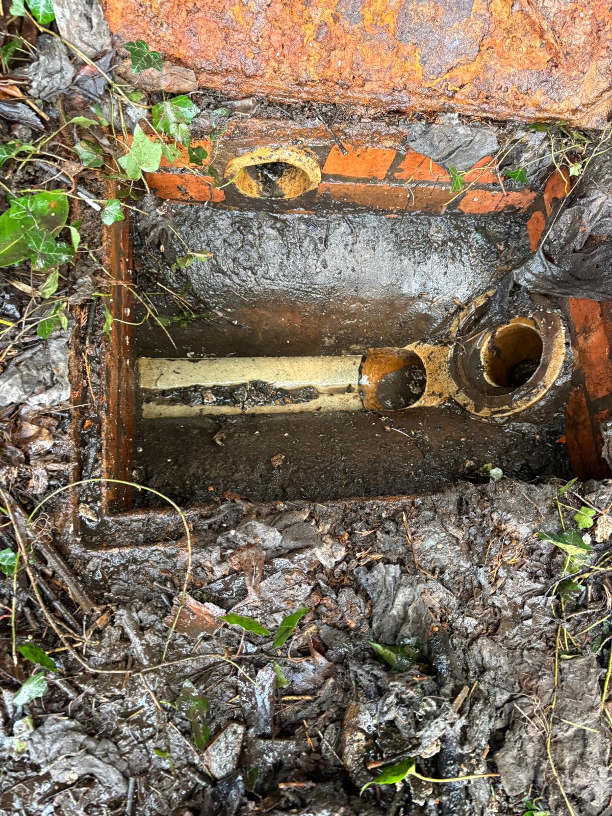 Damaged cracked pipe inside a brick drain chamber awaiting repair in Kent, Surrey, Sussex, Essex & London