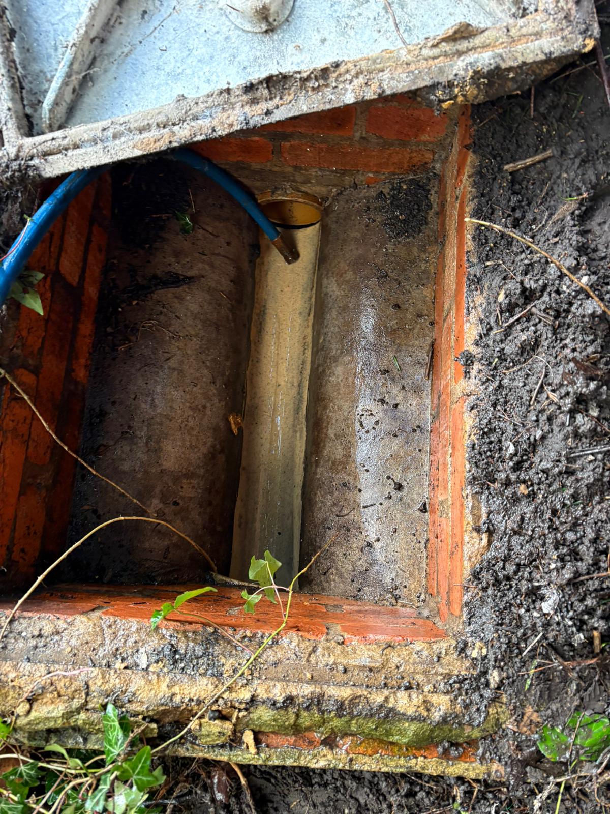 Exposed pipe in a brick drain chamber with a jetting hose during root cutting in Kent, Surrey, Sussex, Essex & London